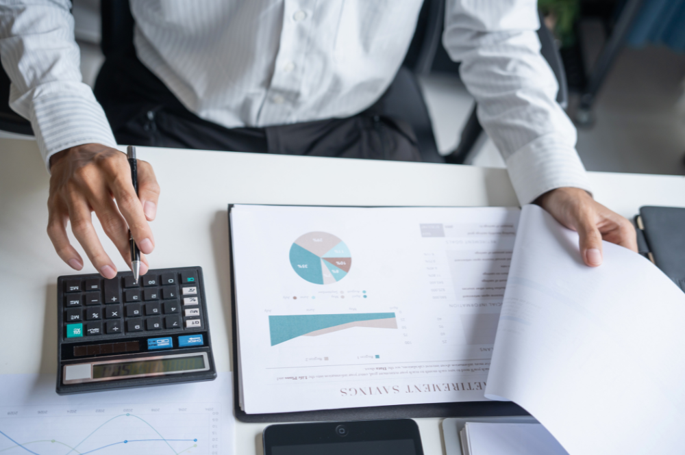 Financial report analysis by a businessman with a calculator, showcasing the functions of private wealth management.